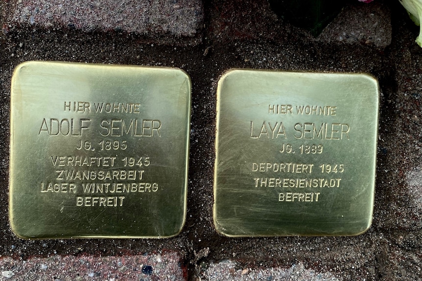 Close up of two bronze, square plaques embedded in a cobblestone street, with names Adolf and Laya Semler engraved in each.