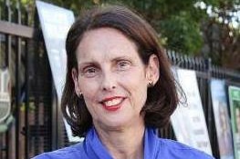 A woman with short brown hair and a lilac dress standing outside