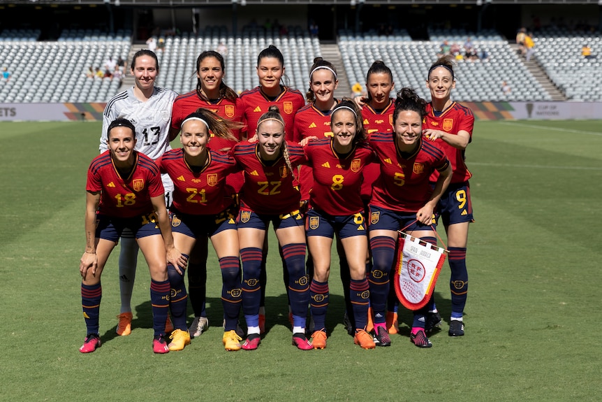 A soccer team wearing red and blue poses for a photo before a game