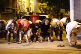 Several men bend at the hips in prayer in the street following an incident involving a van in Finsbury Park.