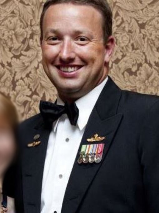 A man in a tuxedo with navy medals.
