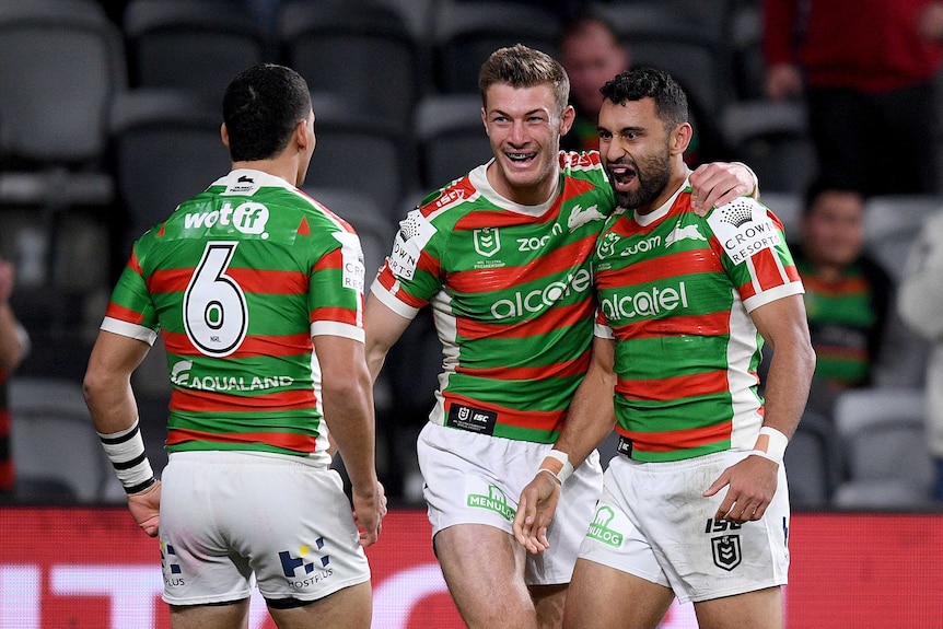 A grinning NRL player gets a hug from a teammate after scoring a try.