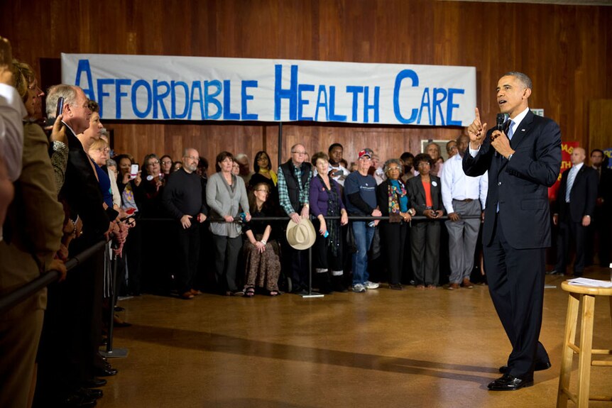 President Barack Obama speaks to crowds in a Texas temple with a large banner behind him reading 'Affordable Health Care'