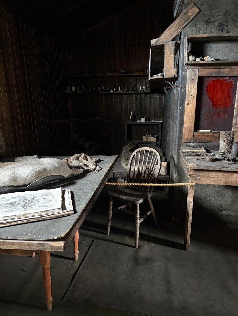 Inside Scotts hut a rope between two wooden tables blocks access to chemicals.