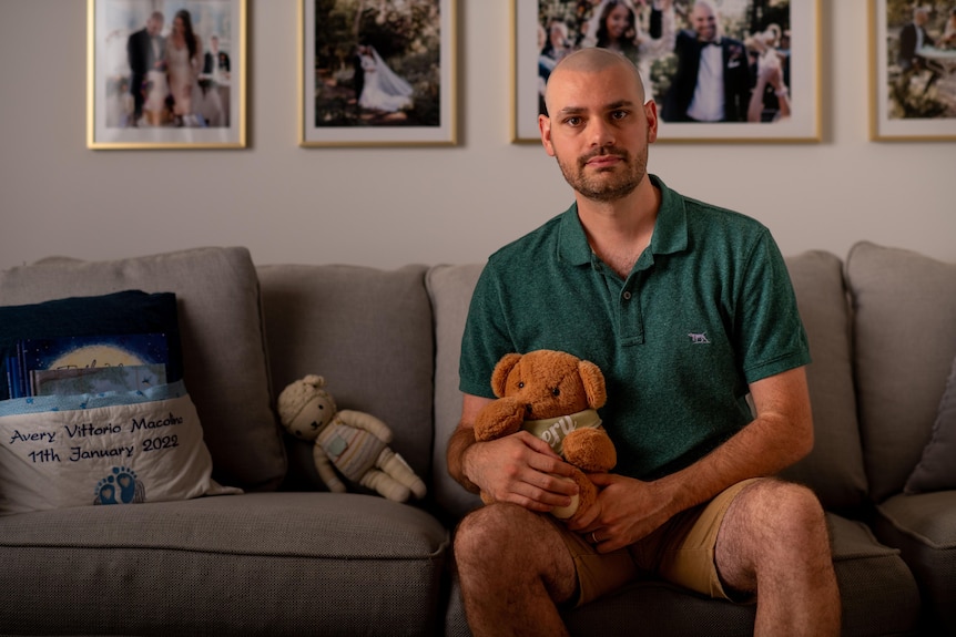 Man holding a teddy bear sitting on a couch. 