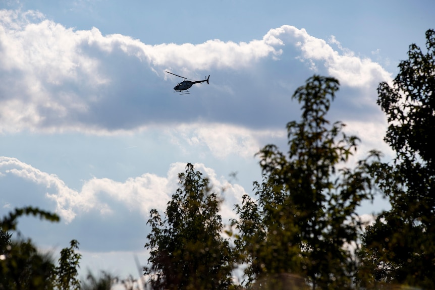 A helicopter hovering above trees. 