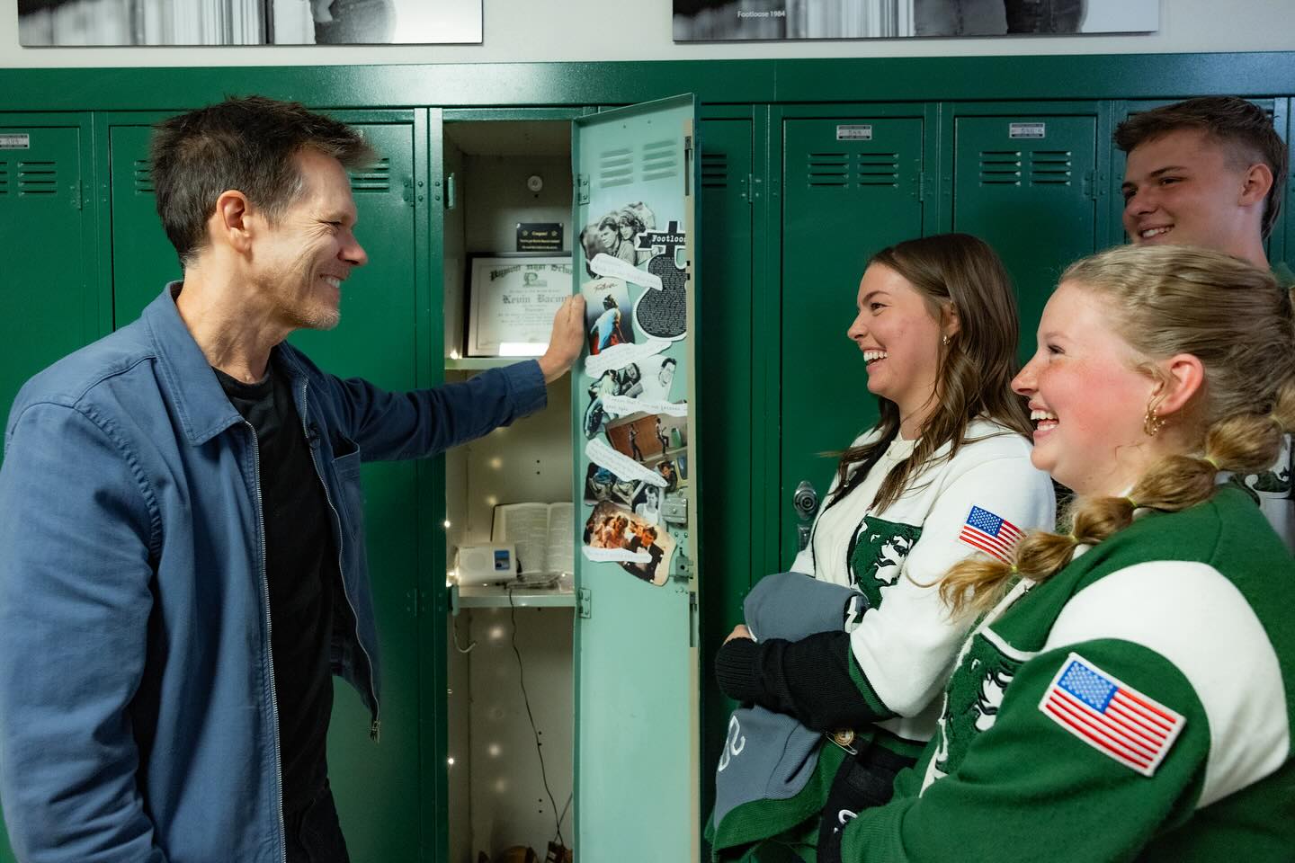Kevin Bacon laughs wiht students in front of lockers