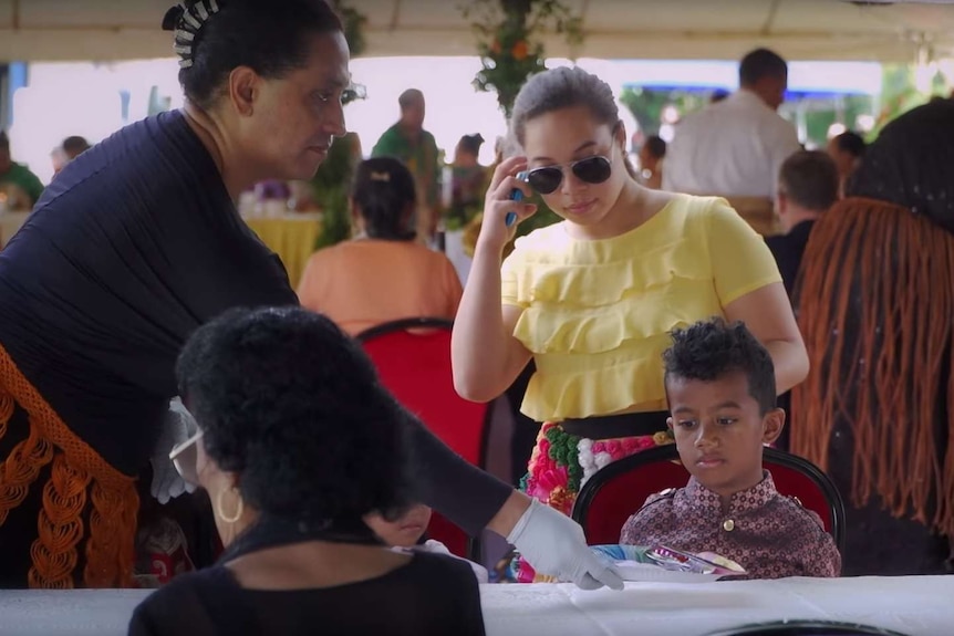 Joey Mataele puts a plate of food in front of a young boy.