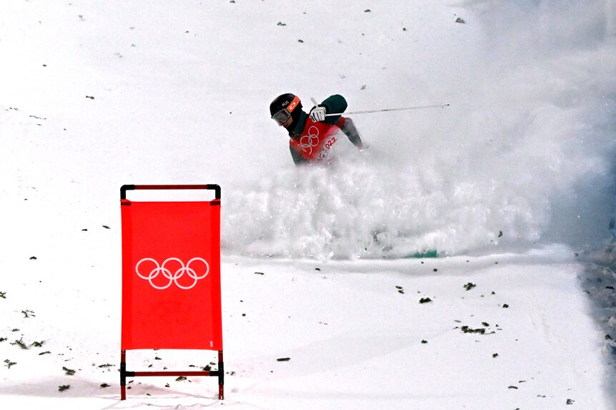 Snow flies up around Matt's body as he skis down a hill