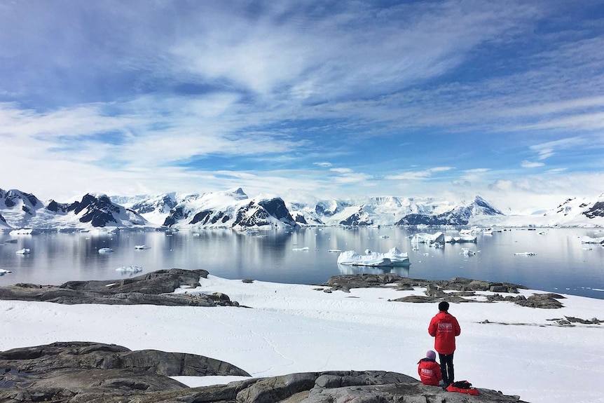 Two people sit on the ice in Antarctica