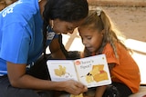 An Aboriginal woman reads Where's Spot with an Aboriginal woman in a blue shirt.