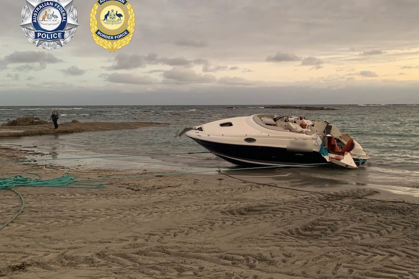 A damaged speed boat being pulled onto a beach