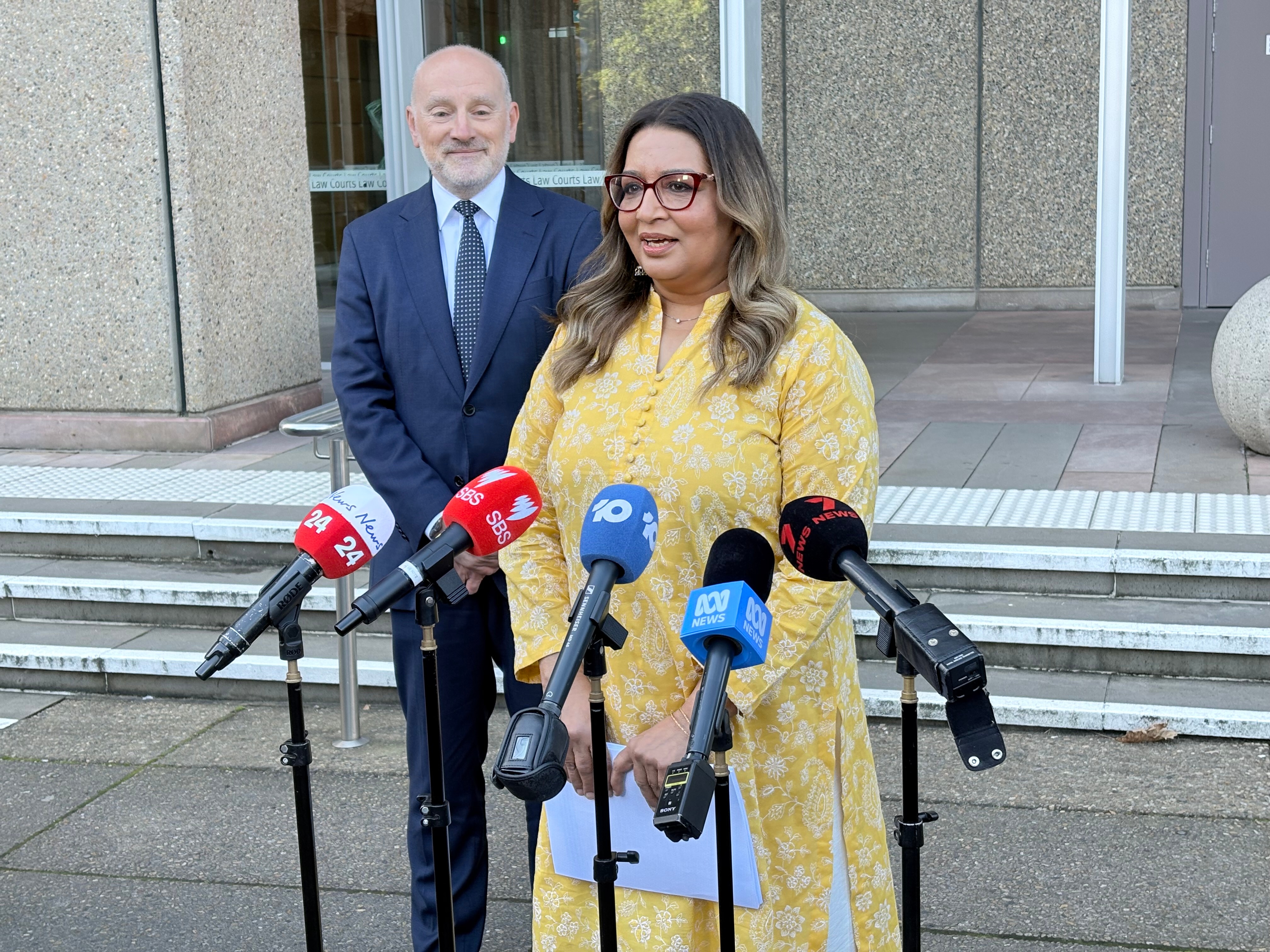 Greens senator Mehreen Faruqi stands behind a microphone addressing the media after a court appearance