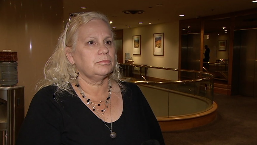 Karen Rogers wearing a black top standing in front of a staircase