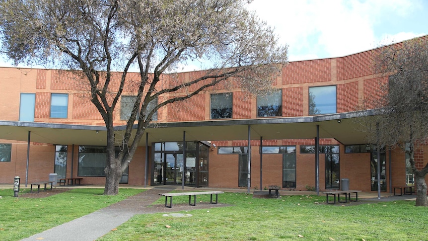 A brick court house with a green lawn and trees.