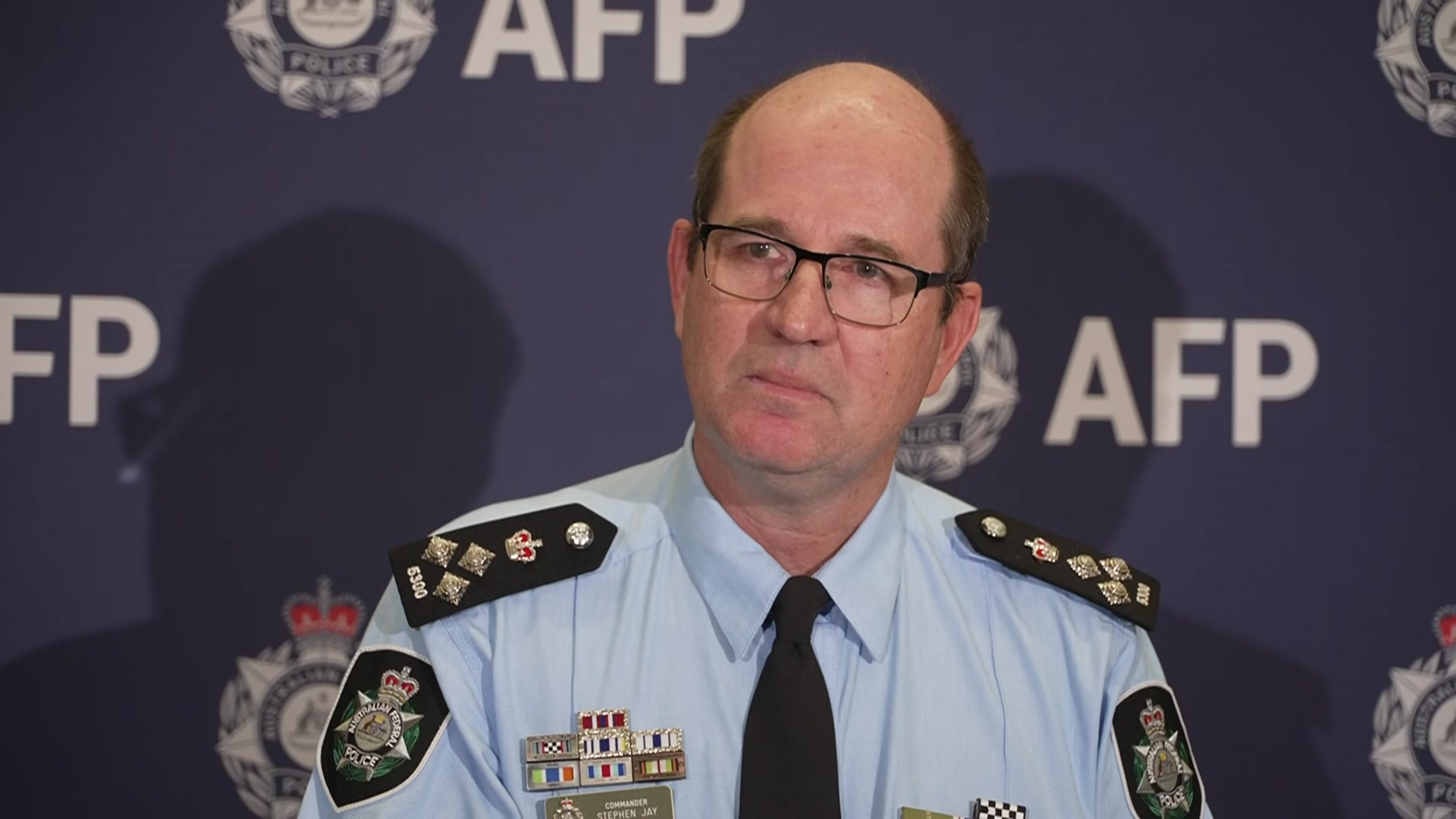 A policeman with glasses in uniform speaking at a press conference.