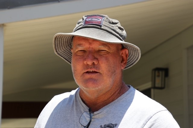 A man in a bucket hat looks into camera