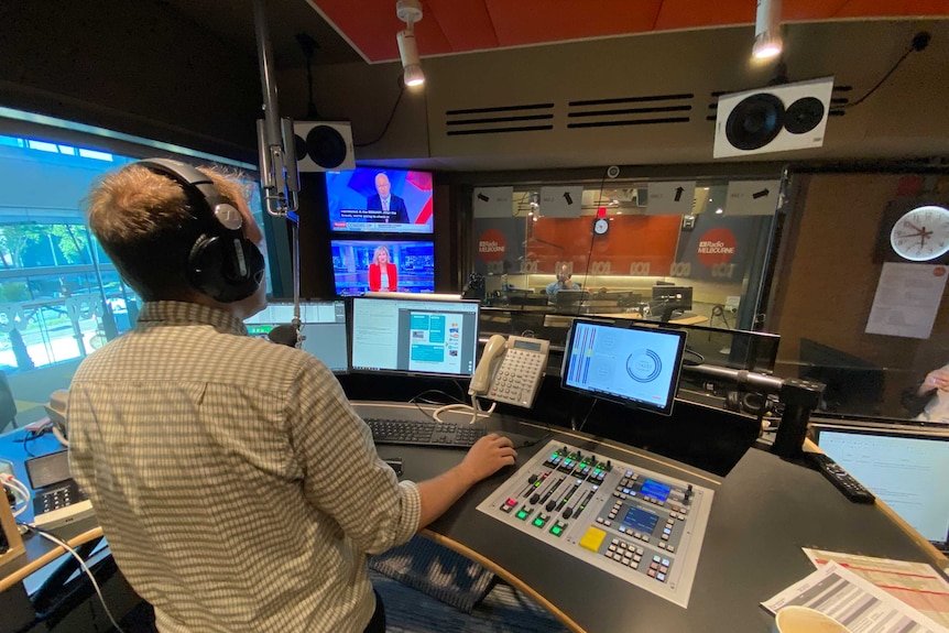 Wide shot ABC Radio Melbourne studio and control room with producer at desk.