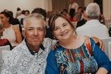 James Bugeja sitting next to his wife at a formal dinner event.