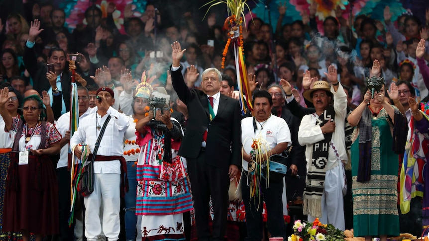 Mexico's new President Andres Manuel Lopez Obrador stands with people dressed in traditional indigenous clothing.