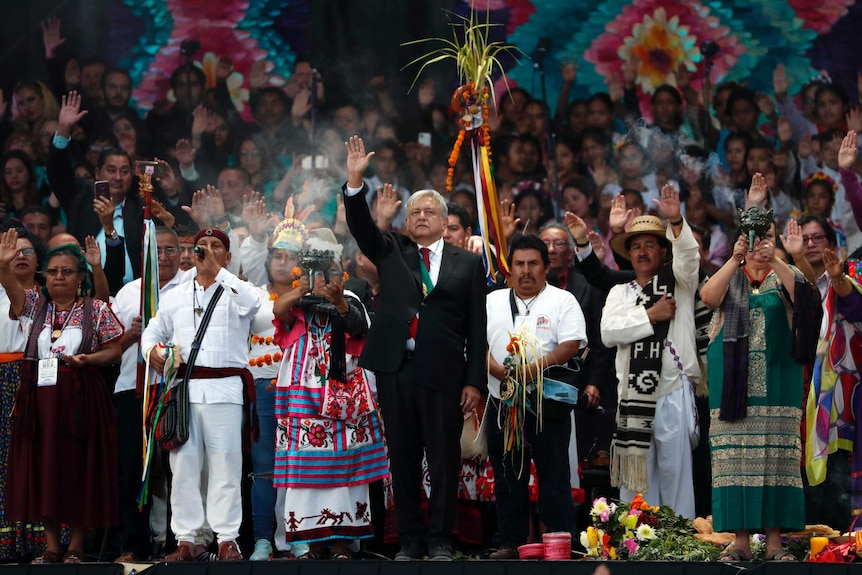 Mexico's new President Andres Manuel Lopez Obrador stands with people dressed in traditional indigenous clothing.
