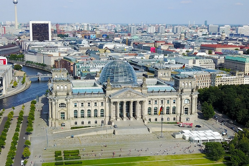 An aerial photo shows a neoclassical building with a contemporary glass dome placed on top of it in Berlin.