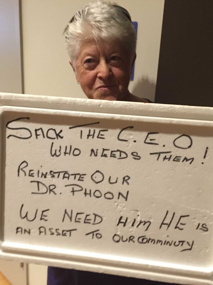 A woman holds an esky lid with a protest message on it