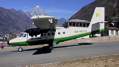 A Tara Air Twin Otter 400 series plane on a runway with a Himalayan mountain in the background