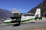 A Tara Air Twin Otter 400 series plane on a runway with a Himalayan mountain in the background