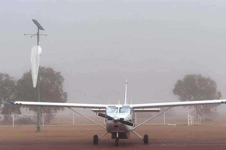 A light plane at an airstrip surrounded by thick fog.