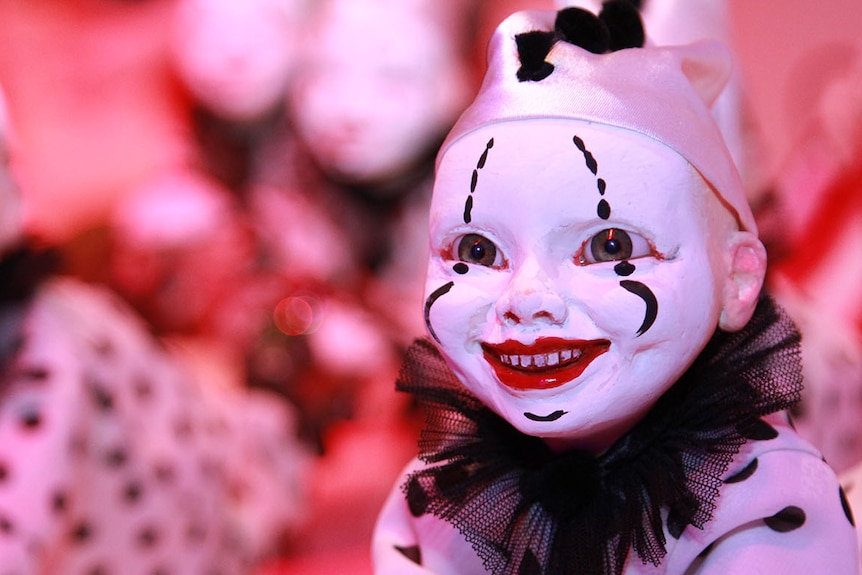 A smiling clown figurine with red lips, a white face and a black and white spotted costume.