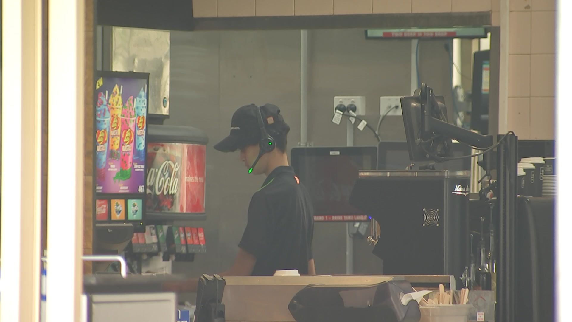 Un empleado de comida rápida frente a una máquina de bebidas