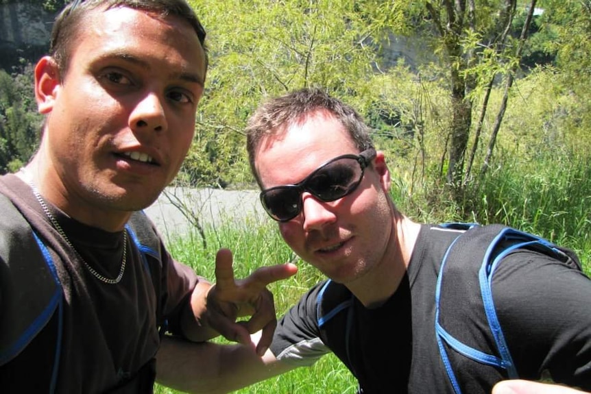 Two men pose together smiling ahead of a BASE jumping mission in NZ.