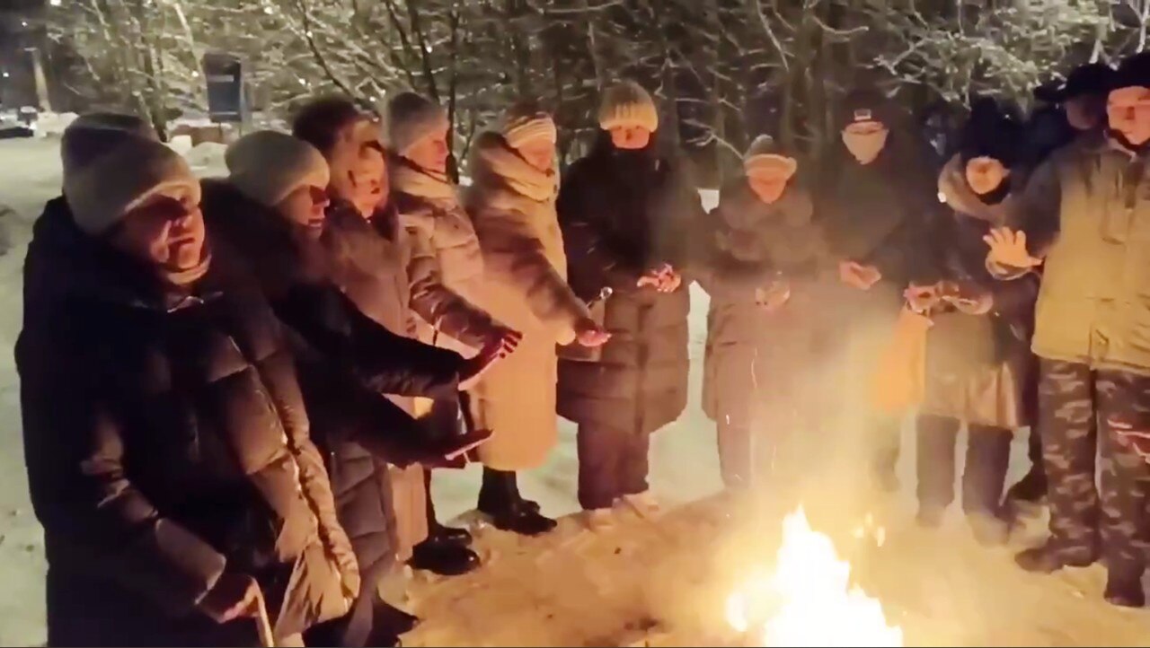 A large group of people around a fire, at night