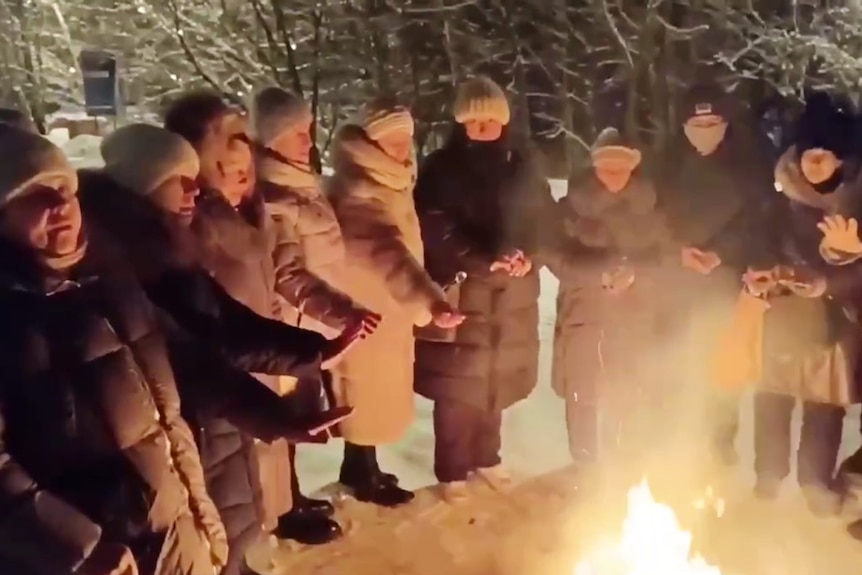 A large group of people around a fire, at night