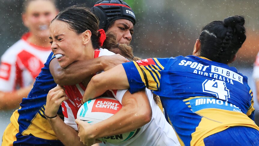 A woman is tackled during a rugby league match 
