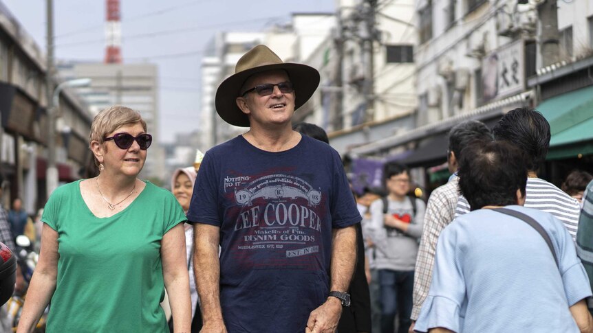 Australian tourists Ross and Jan Cox wander through the market.