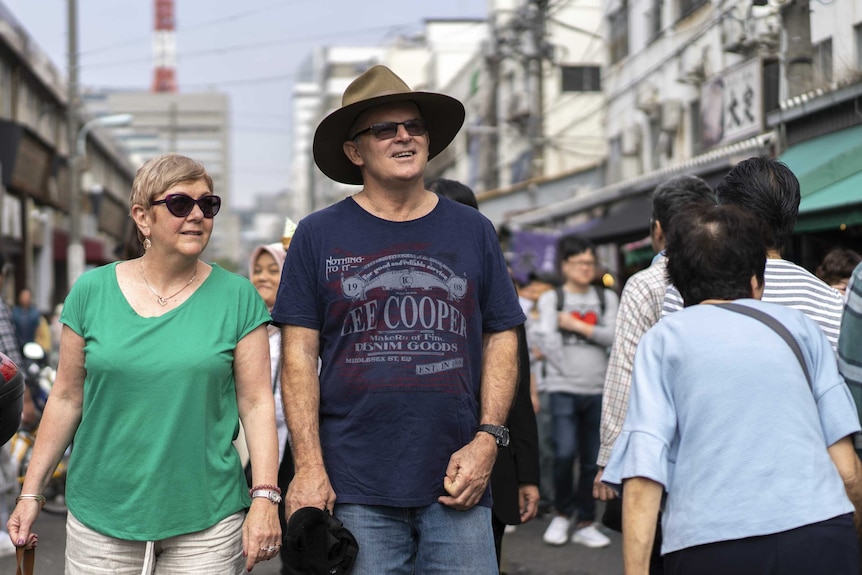 Australian tourists Ross and Jan Cox wander through the market.
