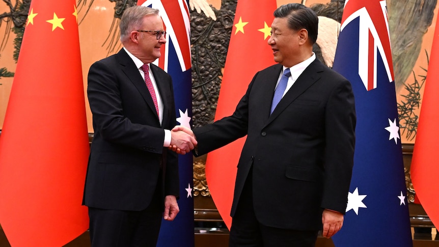 Anthony Albanese shakes hands with Xi Jinping in front of the Chinese and Australian flags.