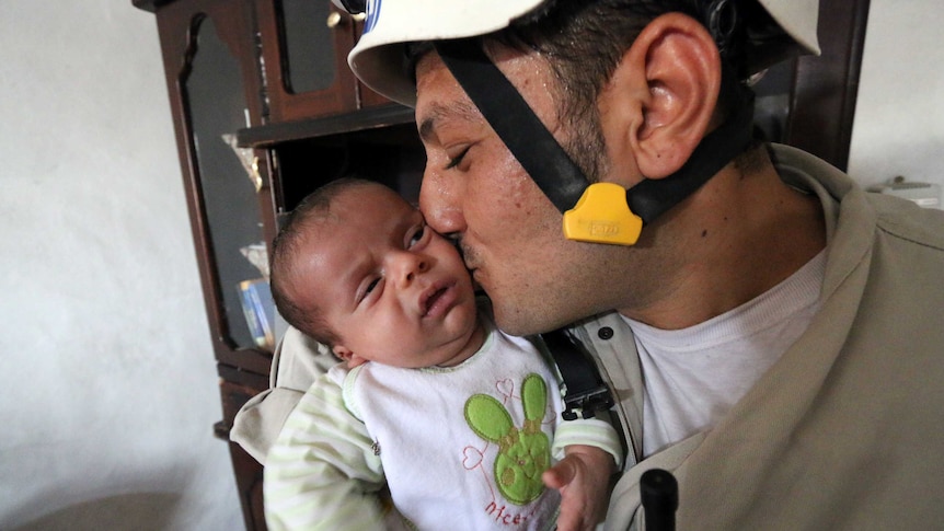 Syrian baby boy with man who rescued him from rubble