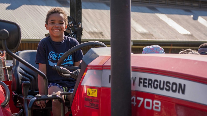A smiling child rides on a tractor at the Collingood Children's Farm