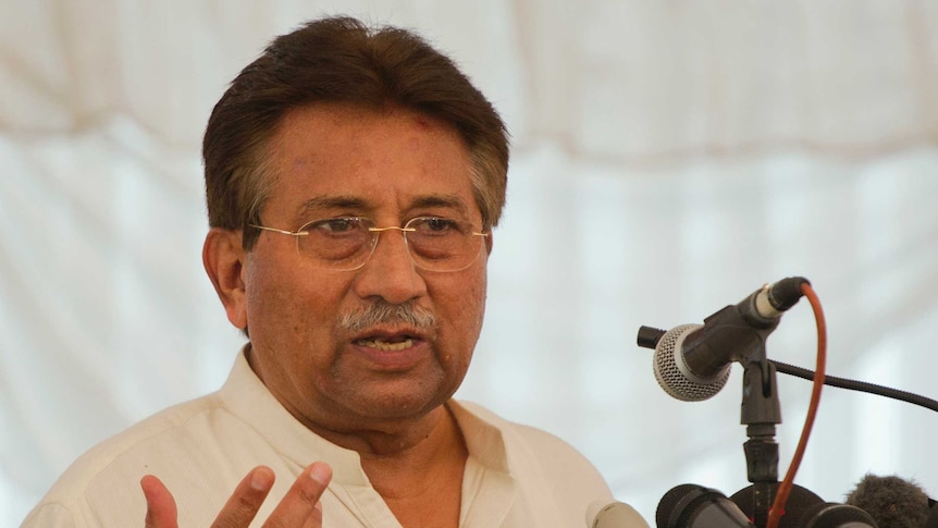 Pervez Musharraf stands at a lectern with microphones. He is wearing a gold ring on one finger.