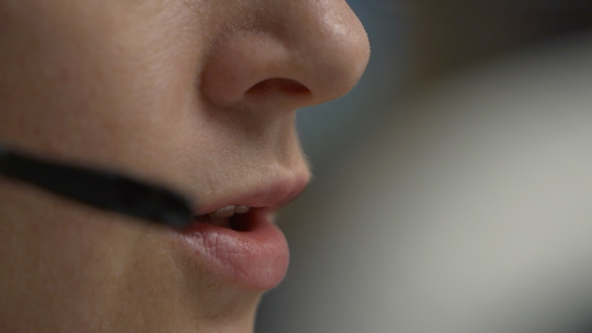 A woman talks into a phone headset.