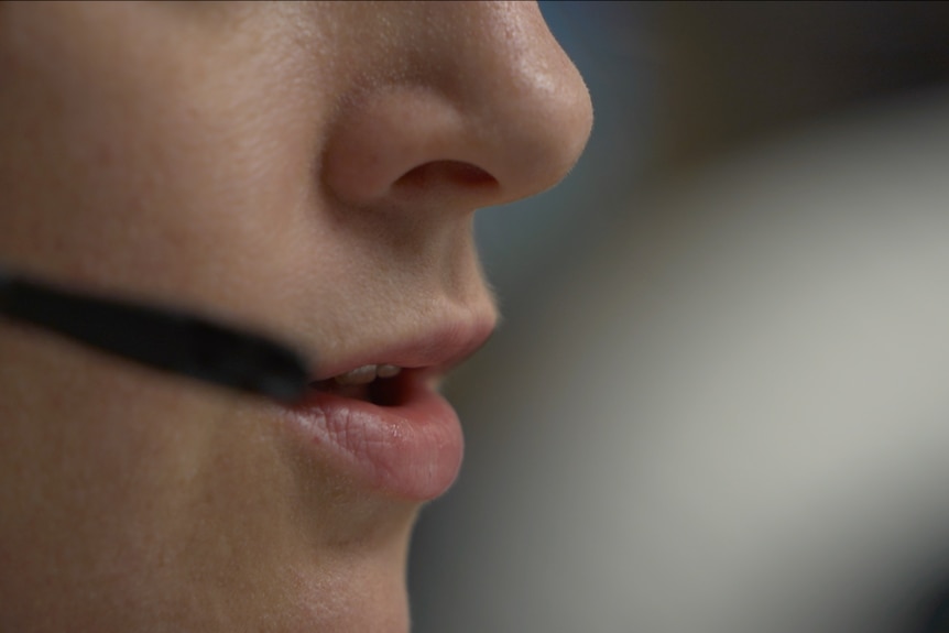 A woman talks into a phone headset.