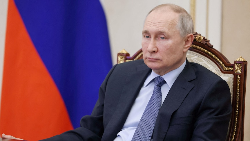 Russian President Vladimir Putin sitting back in his chair during a meeting