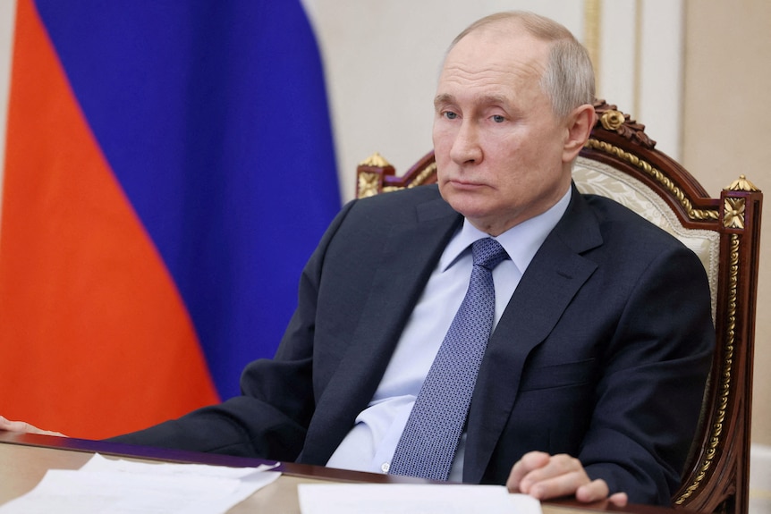 Russian President Vladimir Putin sitting back in his chair during a meeting