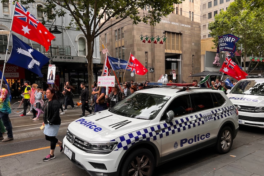 Protesters march through the Melbourne CBD holding flags and signs