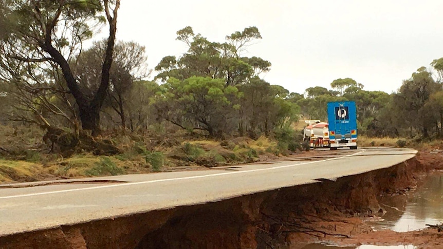 A long stretch of road that has been heavily damaged by flood water.