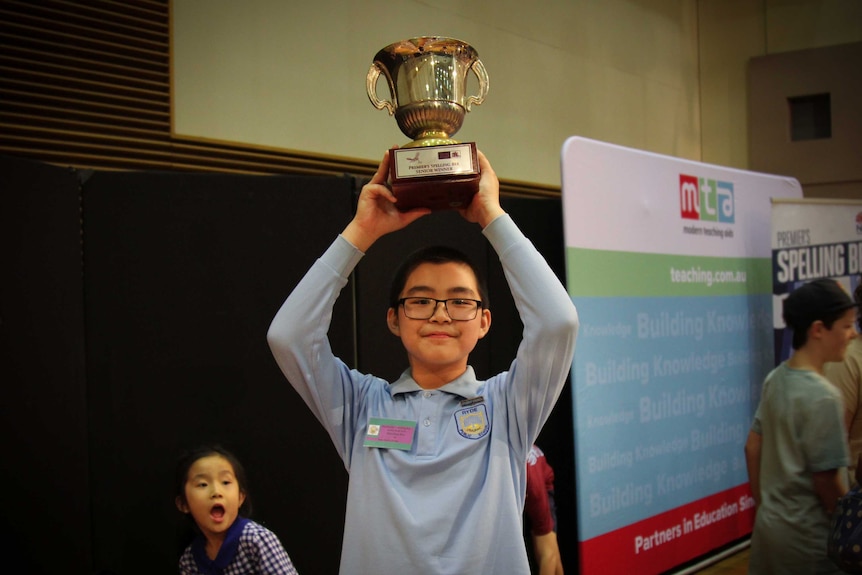 Twelve-year-old McCallum Kho holding the silver trophy above his head.