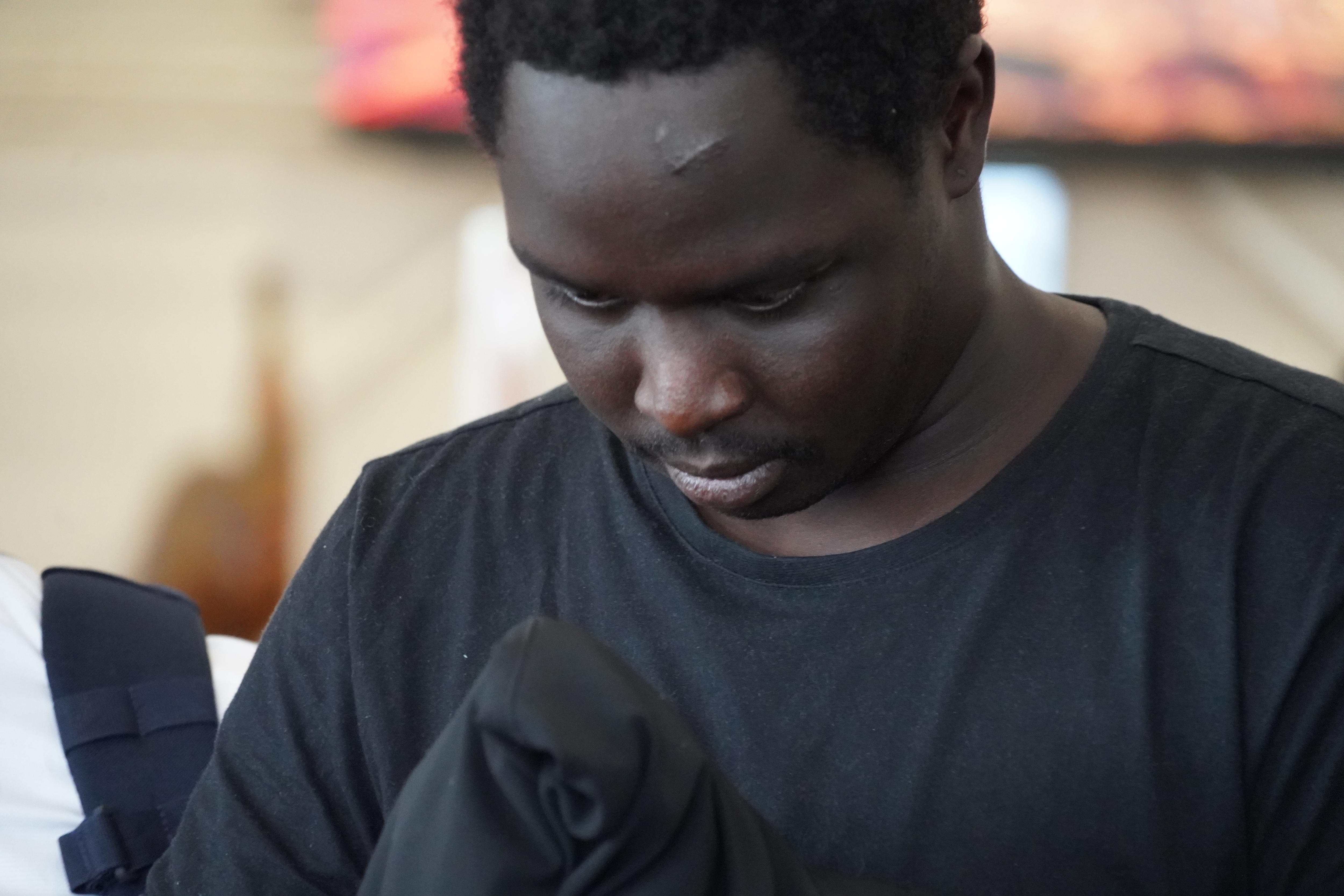 A young black man wearing a black t-shirt walks with his head down